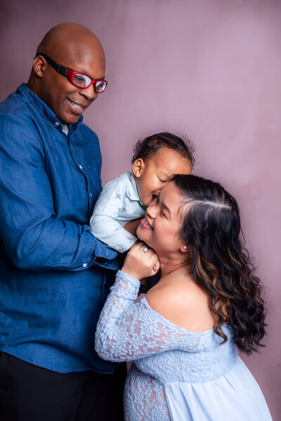 A happy family smiles together for a portrait in a cozy studio setting.