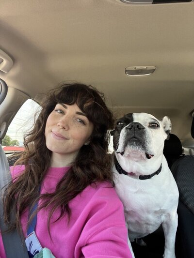 Kelsey in a pink sweatshirt and her dog