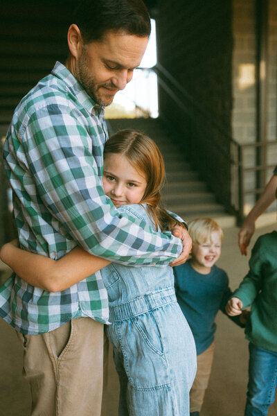 A father hugs his young daughter in a shaded area of downtown marietta, georgia. 