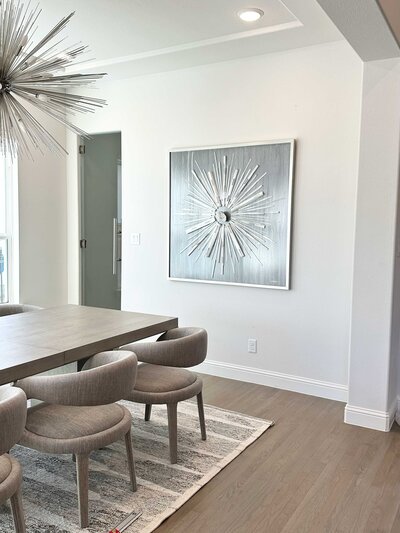 Residential interior design services in a dining room with elegant grey furniture and a beautiful artwork on the wall, adding a sophisticated touch to the space.