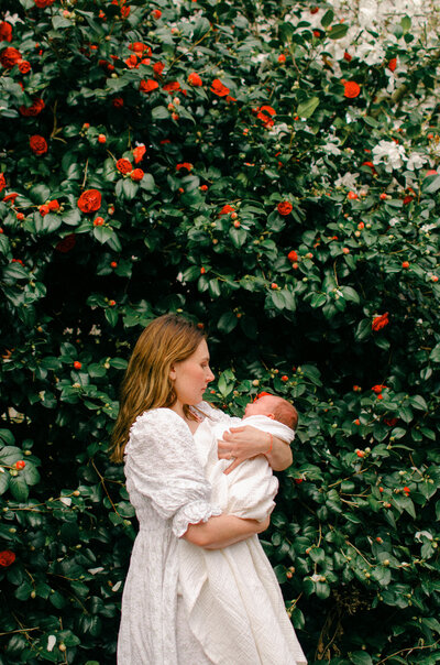 Mother and infant wearing white in the spring flowers at Westerpark in Amsterdam.