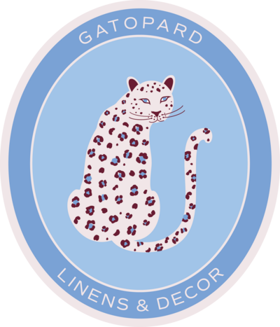 Gatopard Linens & Decor Secondary emblem Logo  featuring oval shape, blush border,  shades of blue  and blush leopard with burgundy and blue spots