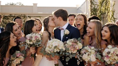 Newly married couple kisses as their wedding party cheers