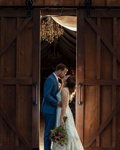 Bride and groom sharing an intimate moment inside a wooden cabin doorway
