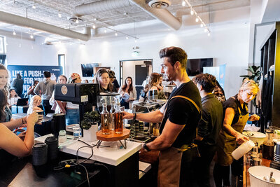 Baristas serve guests at a bustling coffee station during a daytime event at SoHo63, a Chandler wedding and event venue. With natural light, modern décor, and an energetic crowd, the scene showcases SoHo63’s versatility for hosting stylish corporate events and vendor activations.