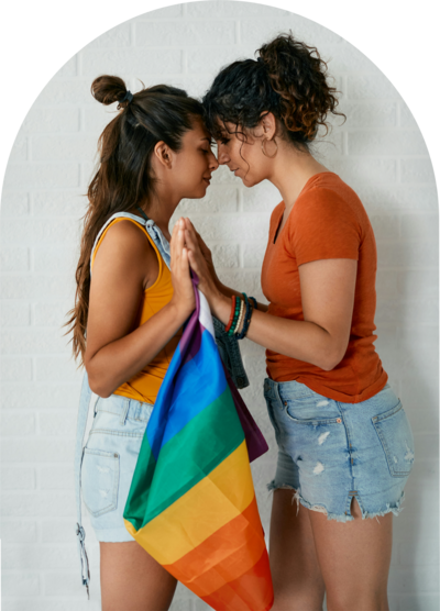 2 females holding a rainbow flag between them
