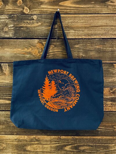 Navy blue custom-printed canvas bag with an outdoor design that has trees and ocean, used as a promo product sold at Newport Brewing Company in Newport, Oregon.