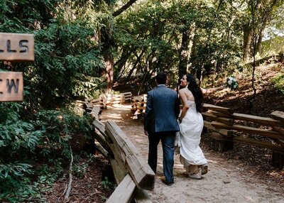 Bride and groom walking on redwood trail.