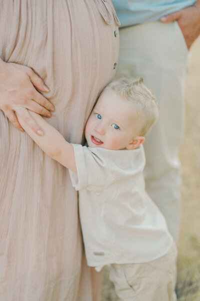 young son hugging mothers pregnant belly