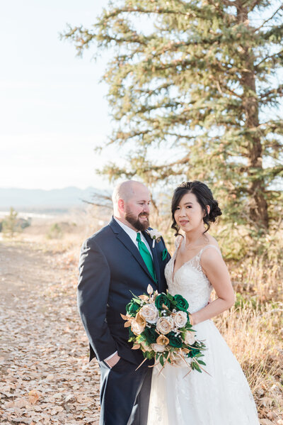 groom holding his bride around the waist as the bride smiles over her shoulder at him captured by denver wedding photographer