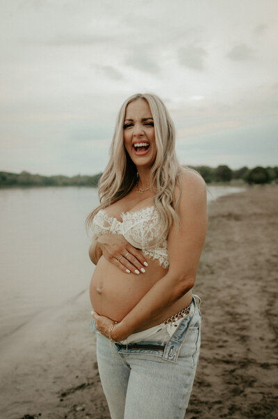 mom laughing while holding her pregnant belly