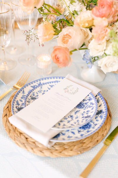 Blue and white floral place setting with rattan charger wedding