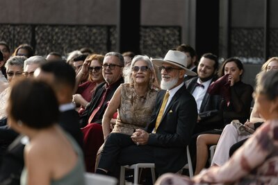Guests smiling and enjoying an outdoor wedding ceremony at Winter Park Events Center in Florida, featuring a stylish elderly couple in elegant attire with joyful expressions.