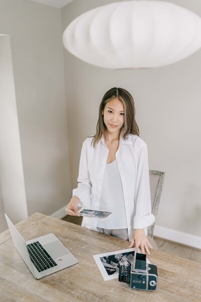 villa works by a desk with her laptop and photos at her studio in Washington D.C. 
