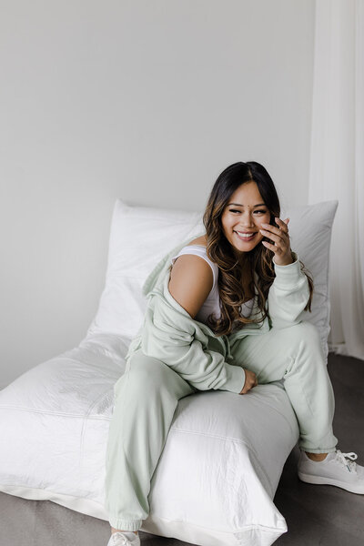 Woman business owner in a smart cream blazer smiles at the camera with her smart phone in hand