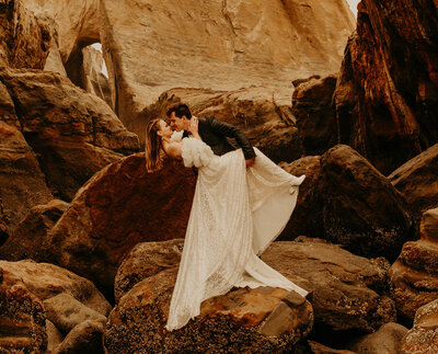 Married couple about to kiss while groom carrying her bride on a rock formation