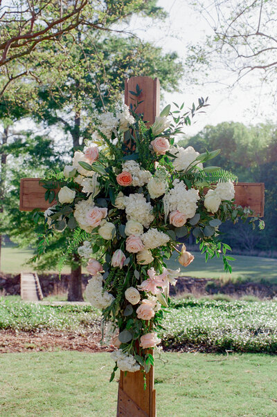 wooden cross in field with florals on it 