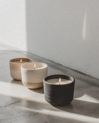 Three softly lit candles in ceramic holders casting warm light, symbolizing grounding, calm, and nervous system regulation in trauma therapy with Jessie Withers, California
