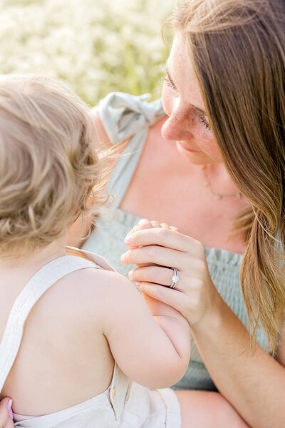 Mother plays with infant in overalls in a Minnesota field.