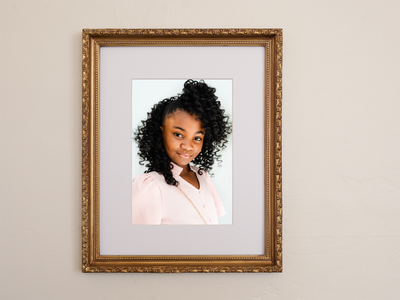 Portrait of smiling girl with curly hair in gold ornate frame.