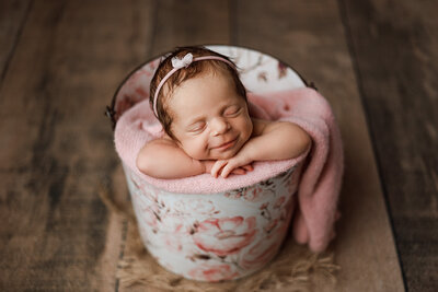 baby girl posed in a bucket with yellow fabric and flowers in professional photo shoot in charlevoix
