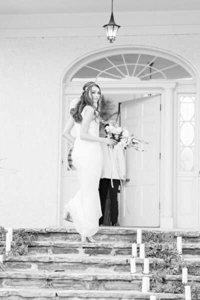 black and white image of bride walking up stairs behind groom at Rust Manor House