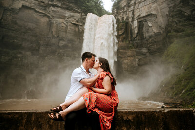 man and woman embracing with waterfall in the background