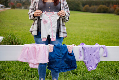 Photo of expecting mother holding baby clothes