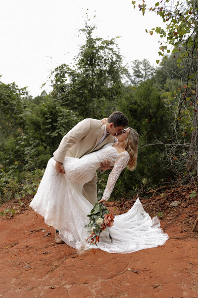 Adventurous elopement moment as couple shares a dip kiss in the red rock canyon after exchanging vows.
