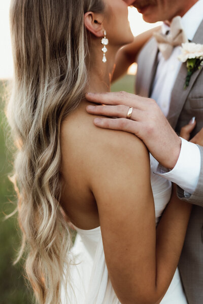 Close of up brides earrings and grooms wedding ring while they are outside dancing in an outdoor wedding venue. 