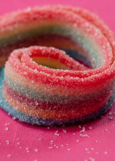 Rainbow sour candy ribbons on a pink background