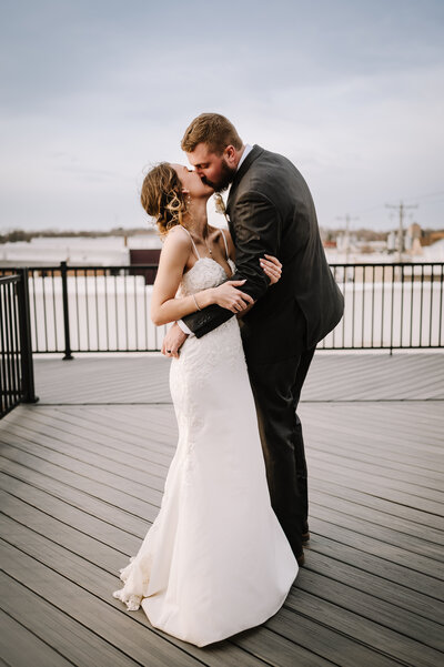 Bride and groom kissing on a rooftop.