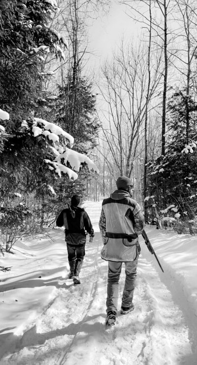 black and white image of two people walking in the snow