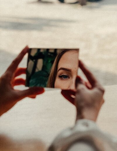 A symbolic representation of mid-life crisis help, featuring a woman reflecting on herself through a mirror. Coaching for women seeking clarity, healing, and transformation during major life transitions.