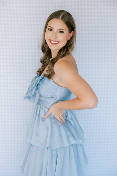 A Mississippi wedding photographer smiles big in front of a gingham background.