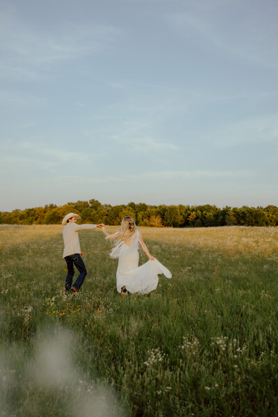 couple running through a field of wildflowers at their wedding venue near okc