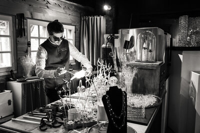 A glass artist shaping his creation in the atelier using a burner.