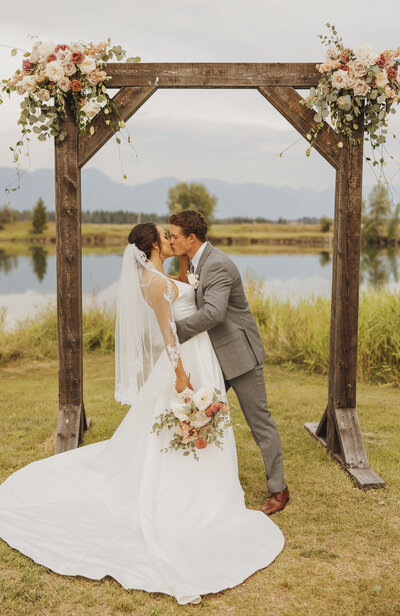 bride and groom kissing under arch