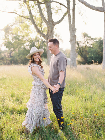Couple holding hands and smiling in a grassy field