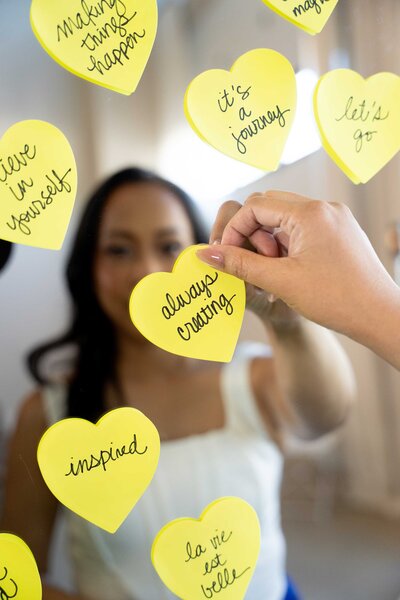 Branding photographer for business placing a yellow sticky note with a powerful quote on a mirror, reflecting her professional identity and creative brand photography style