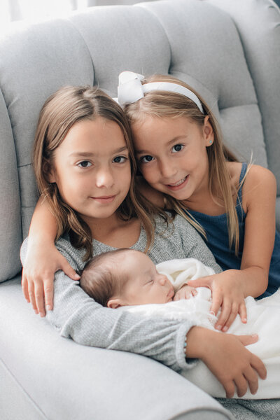 Big sisters holding their new sibling baby