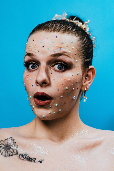 Creative makeup on a woman with a bright blue backdrop