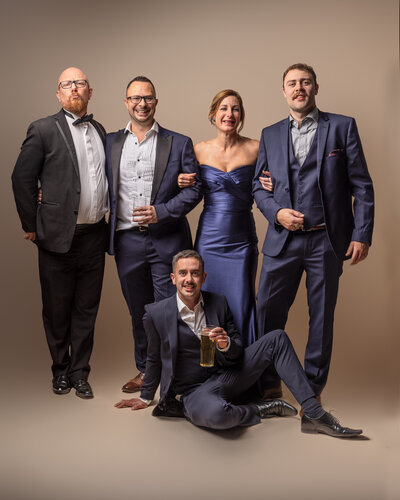 Image of 5 work colleagues at a black tie dinner posing for an image together on a backdrop. 