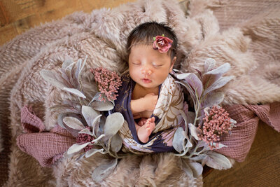 Newborn baby girl surrounded by mauve and florals