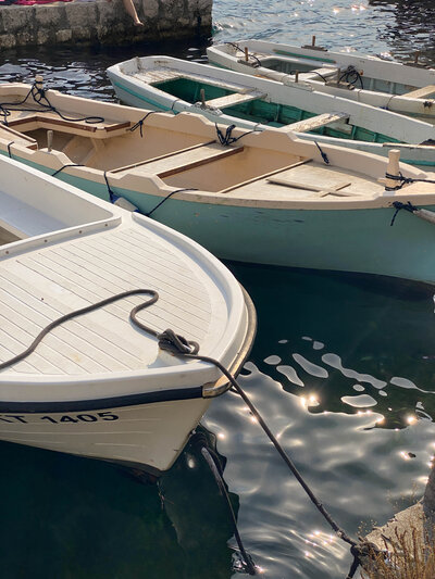 Colorful boats docked at Mediterranean marina ready for travelers to embark on a coastal adventure. Tailored Oasis Travel Co.