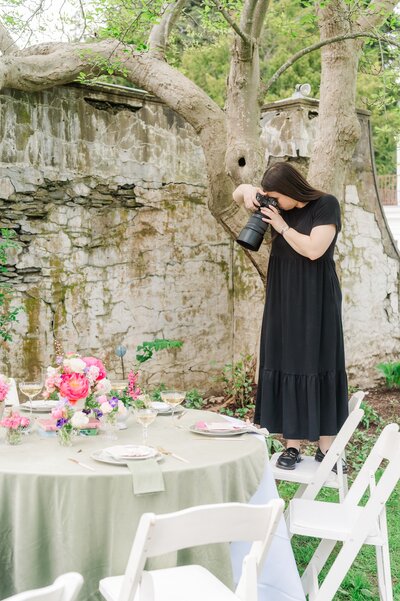 Ephe standing on a chair taking photos of a table setting at Gwyn Careg Inn. 