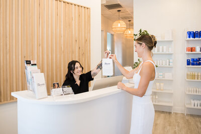 Woman smiling handing client skincare products