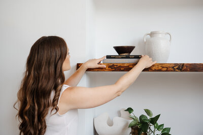 woman placing decorations on a shelf