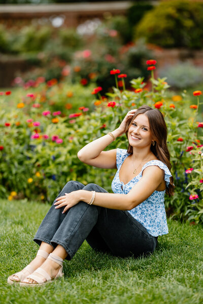 Senior girl smiles at camera in flowery field in Chelmsford, Massachusetts