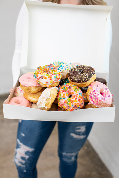 Megan Reyes - Owner - Holing an overfilled box of donuts - Daylight Donuts